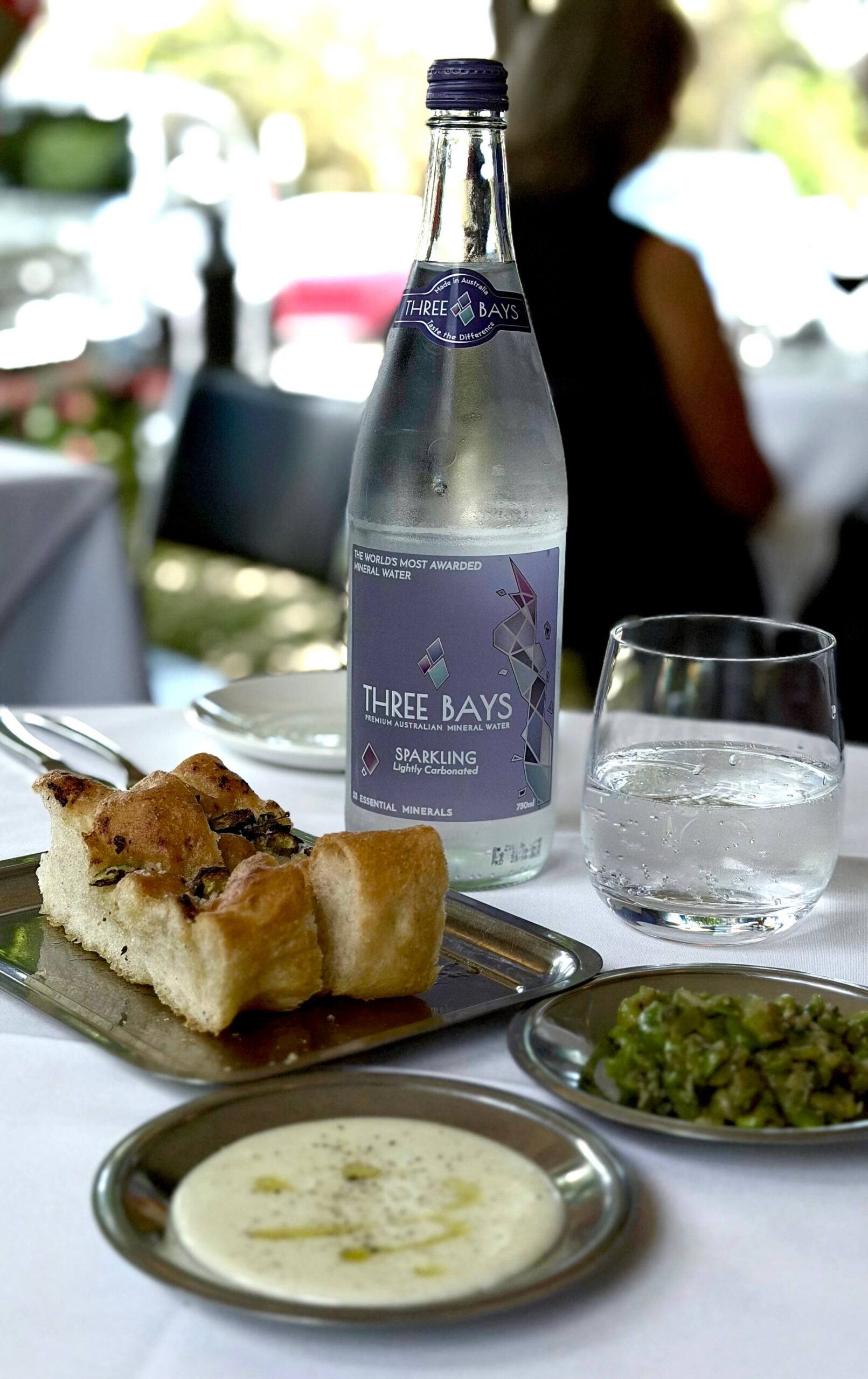 Refreshing bottle of Threebays sparkling water on a table with clean linen in a restaurant.